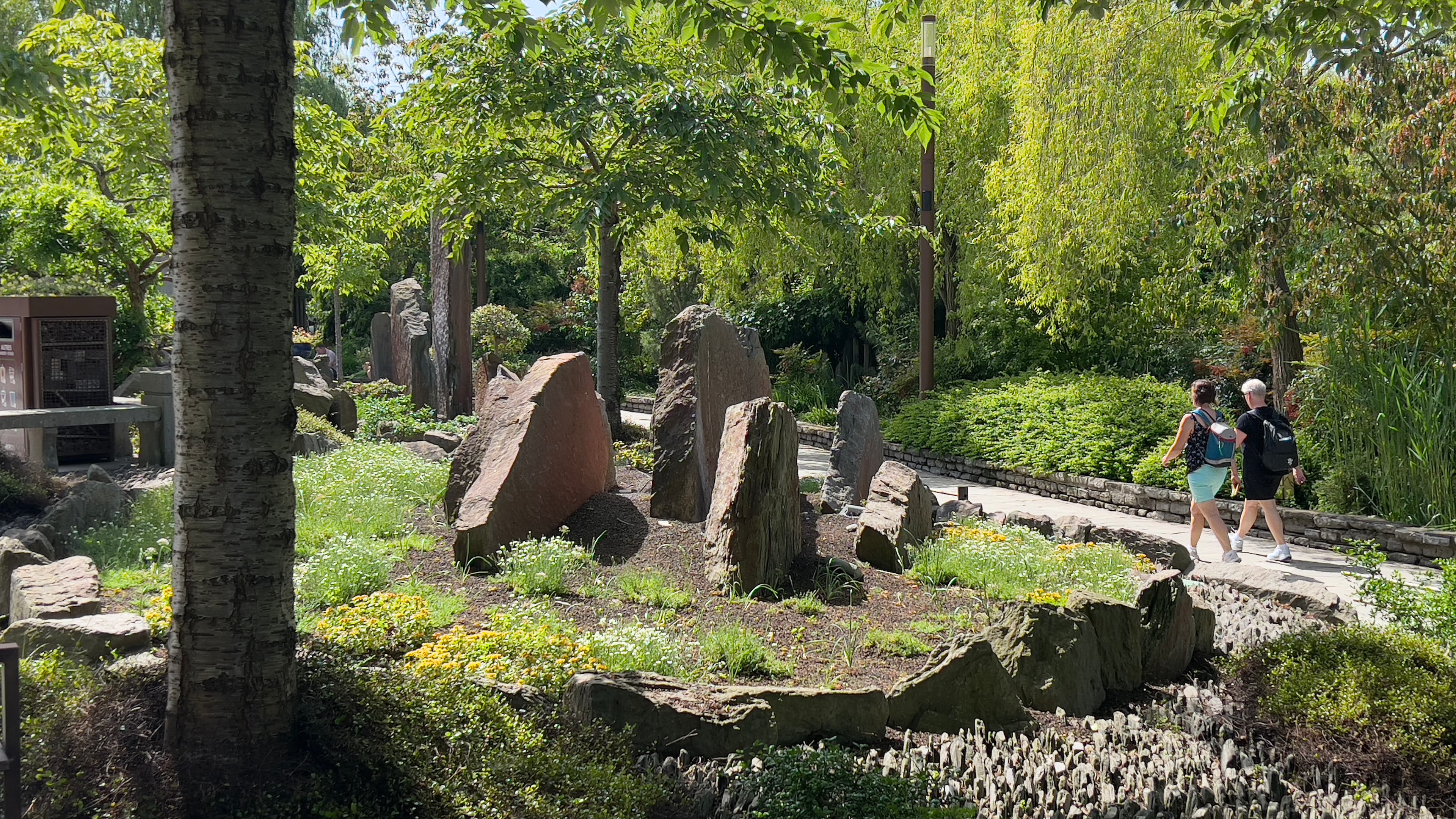 Visitors walking through lush garden with stone formations at Pairi Daiza Belgium